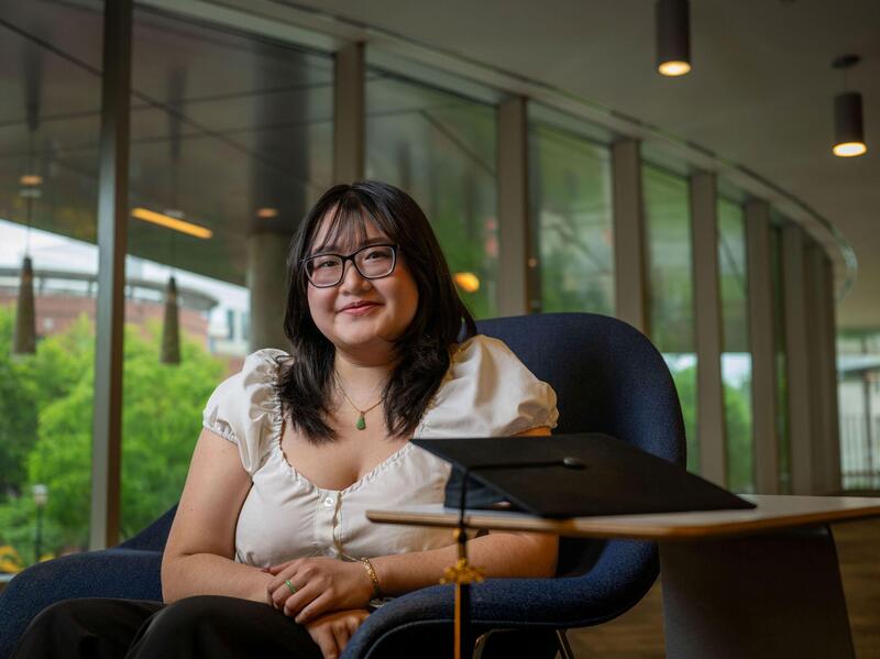 A woman in glasses sits in a blue chair.