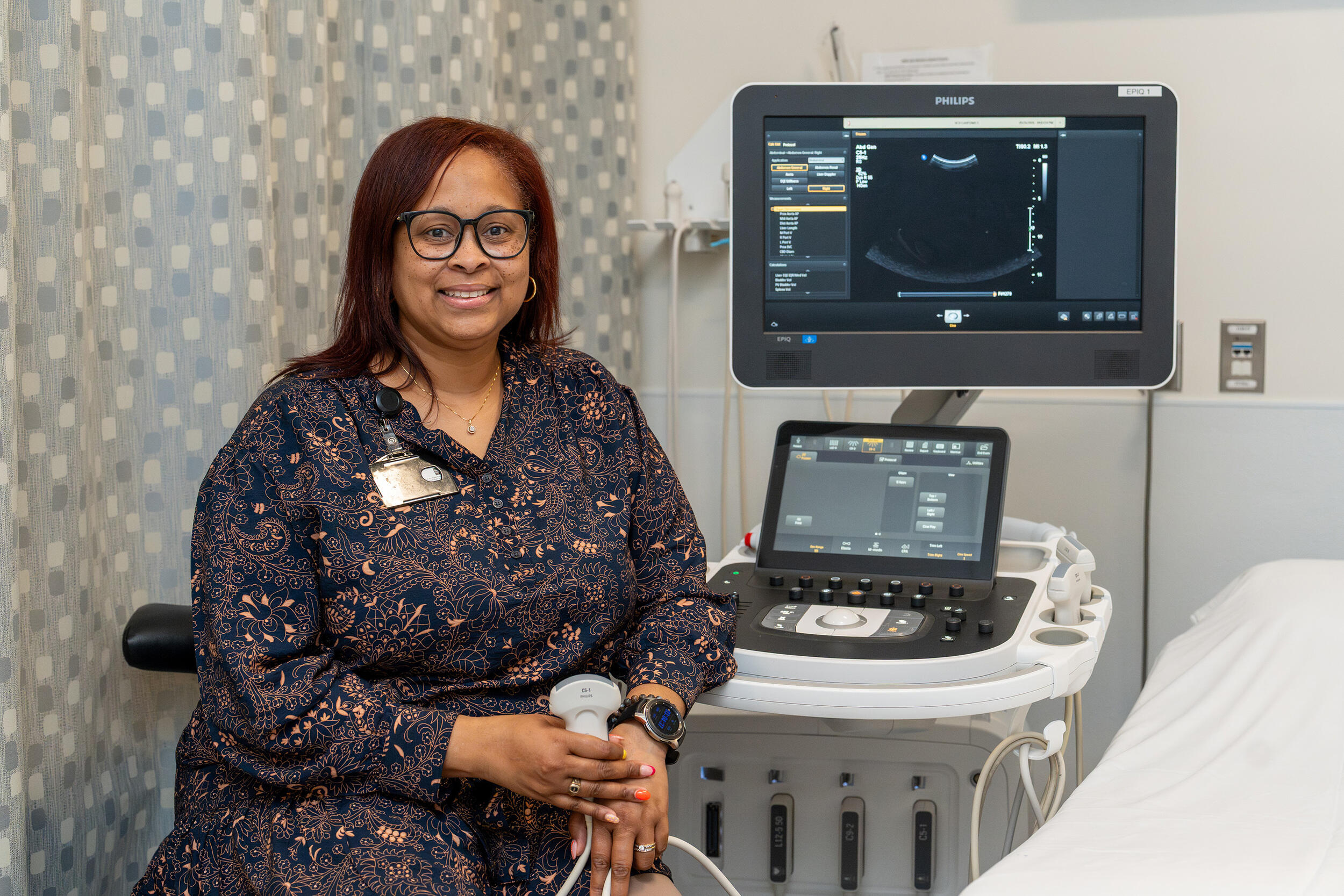 A photo of a woman sitting in front of a sonograph machine.