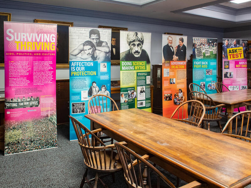 A photo of a room with tables with six banner signs with information on them 