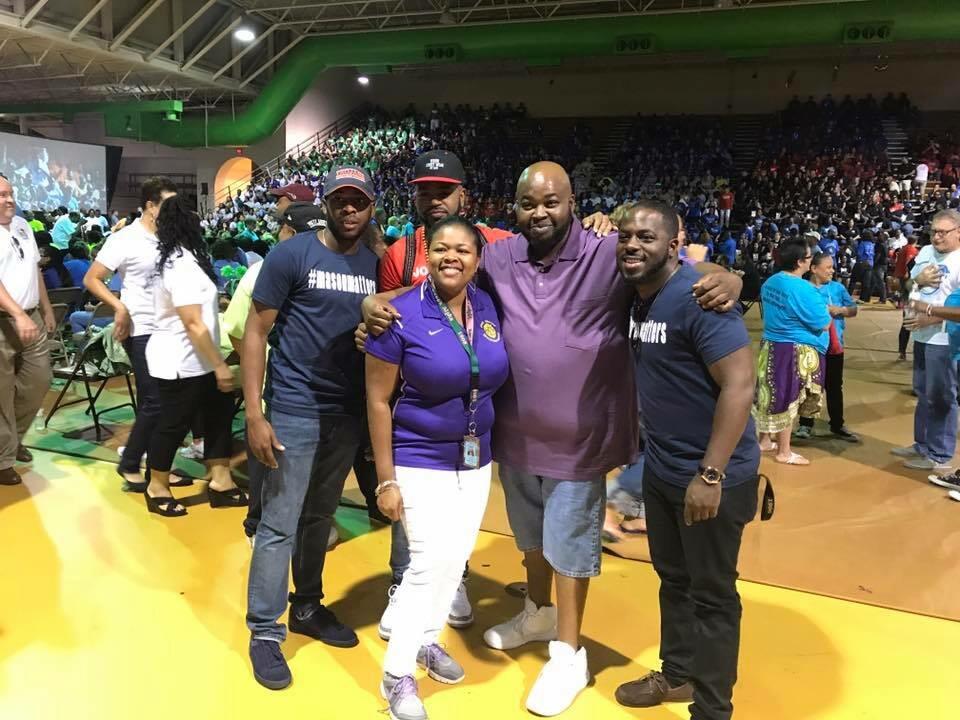 Rodney Robinson stands with the principal of the Virgie Binford Education Center, Ta’Neshia Ford. Surrounding them are a group of Robinson’s students who are now educators.
