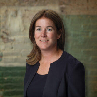 A woman with shoulder length hair wearing a black undershirt and black sports coat 