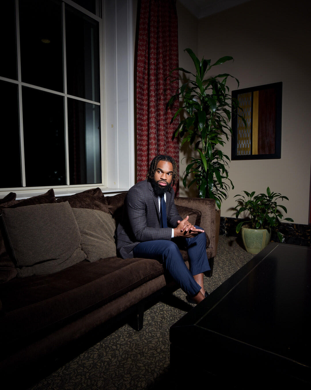 A man sitting at the end of a couch in a dark room 