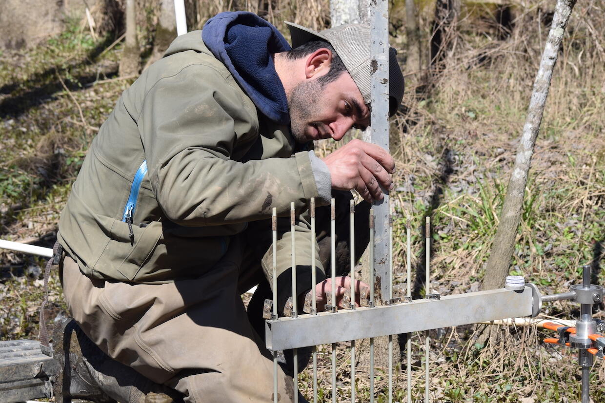 A man making measurements with a metal ruler on a scientific research project.
