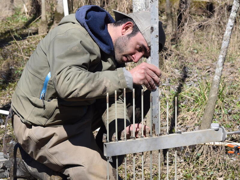A man making measurements with a metal ruler on a scientific research project.