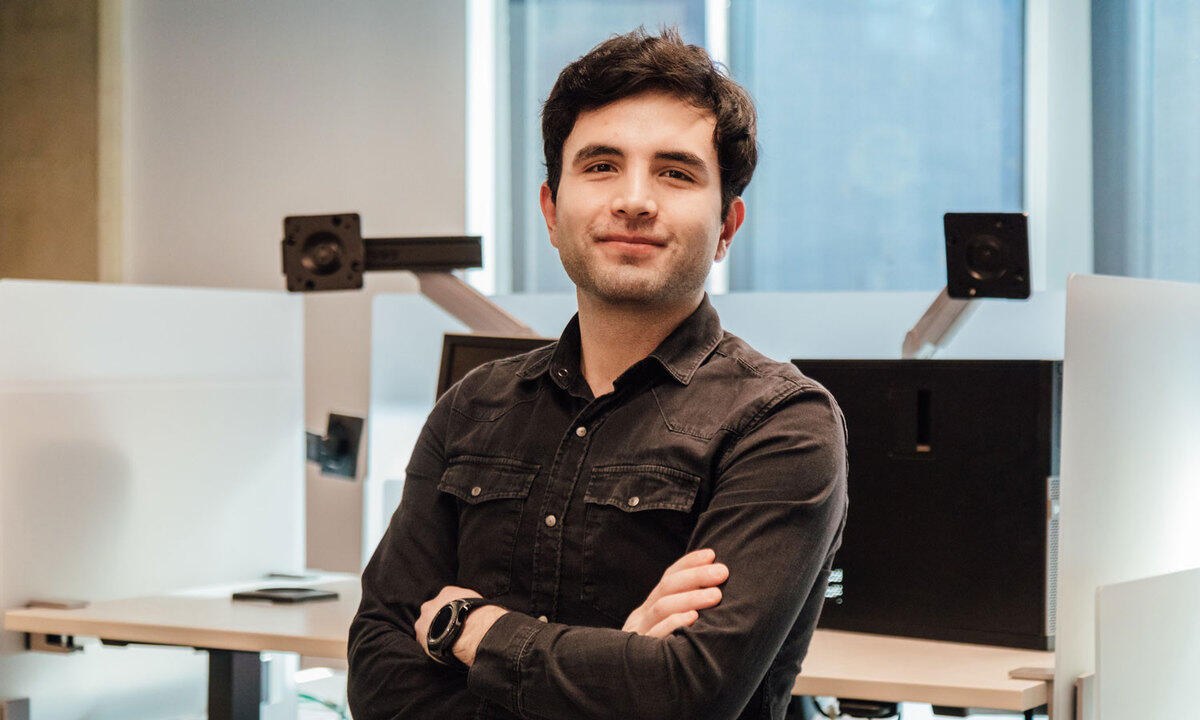 A portrait of a man from the chest up with his arms crossed against his chest. 