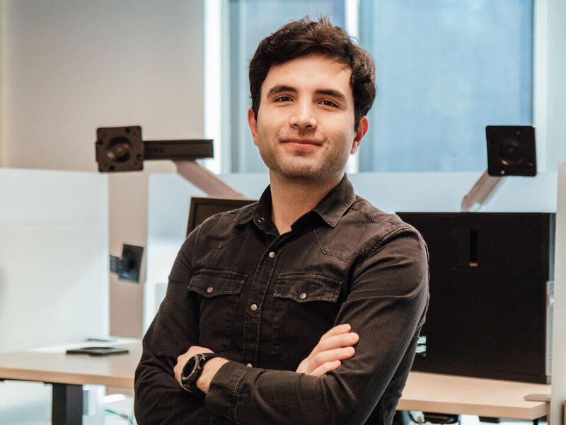 A portrait of a man from the chest up with his arms crossed against his chest. 