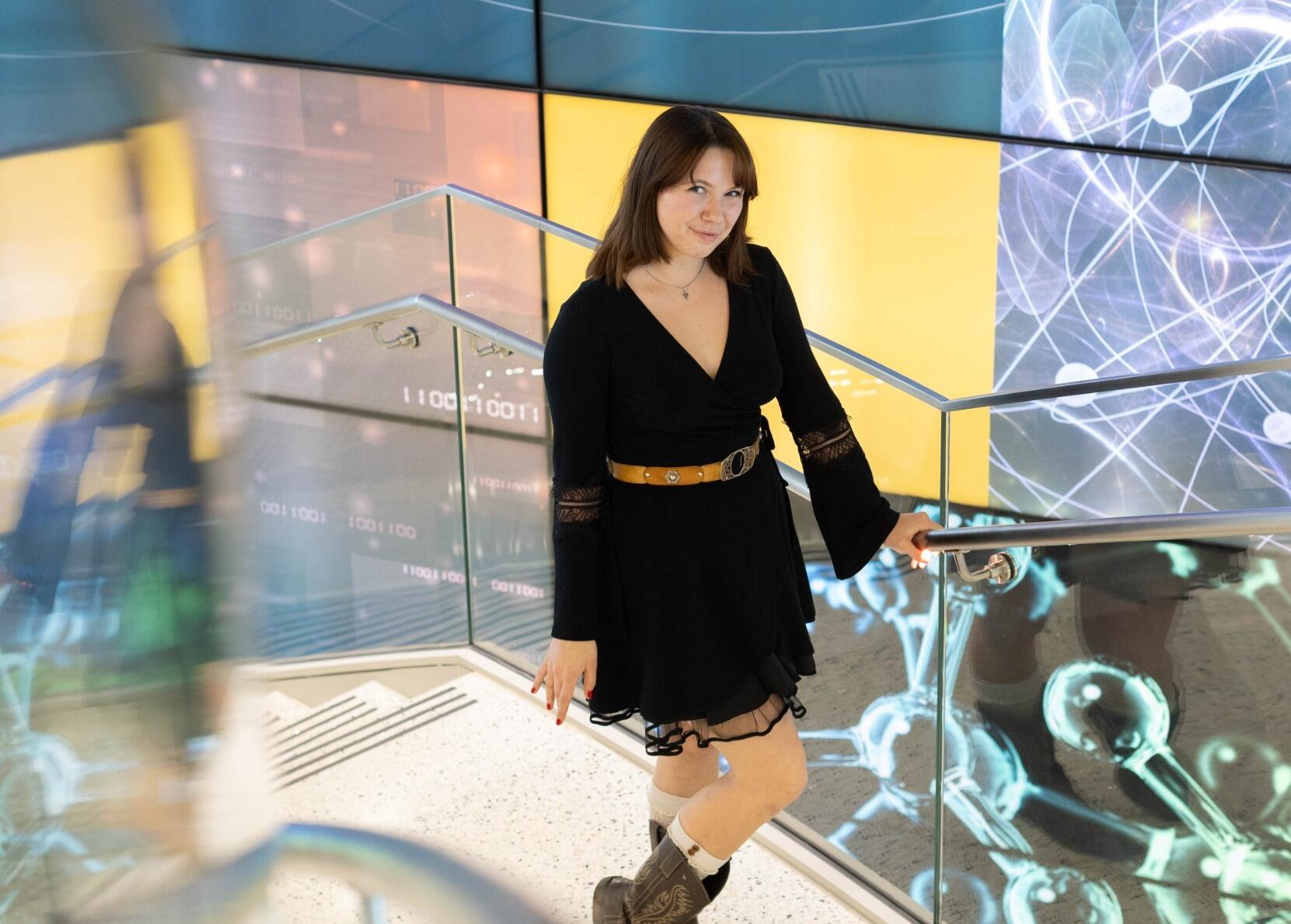 A photo of a woman standing on a staircase. 