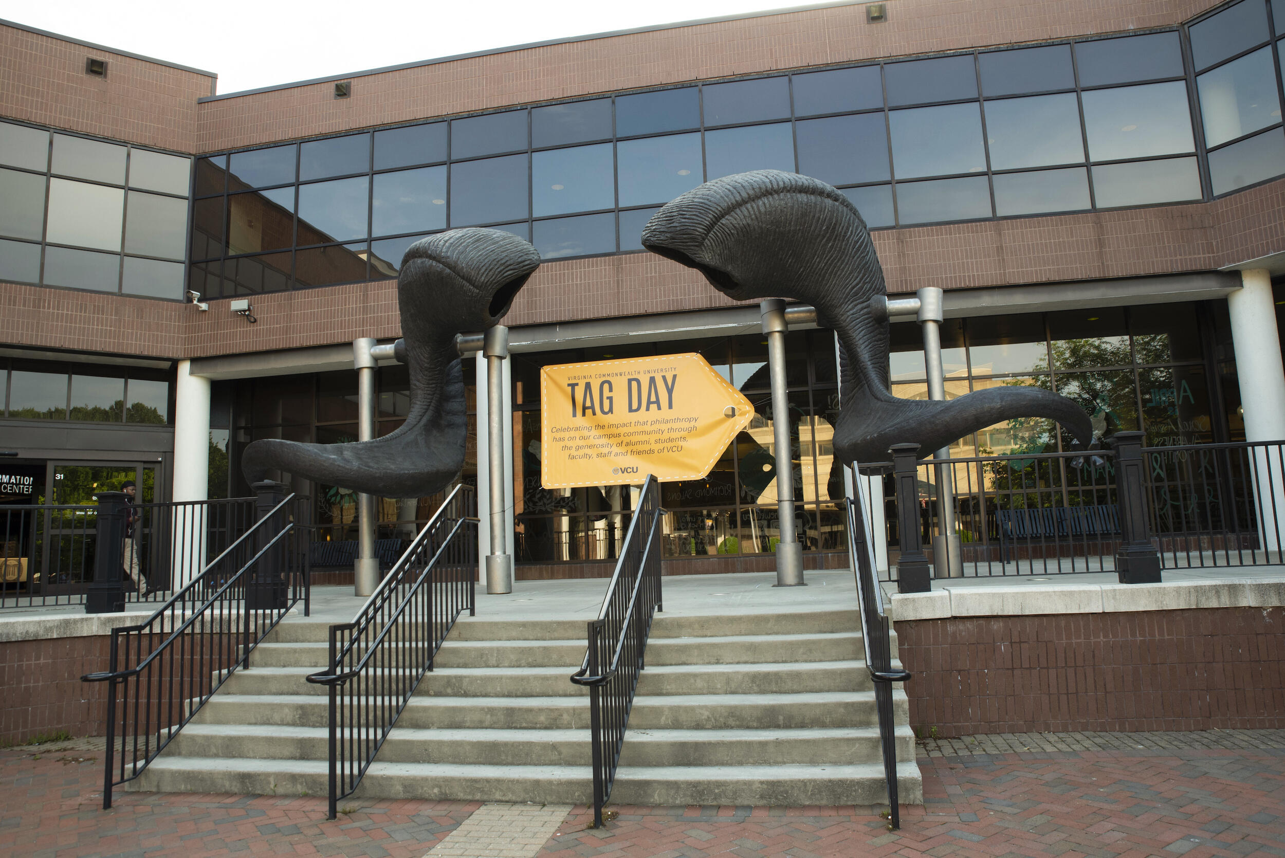 A sign celebrating Tag Day under the ram horn sculpture in front of the University Student Commons building.