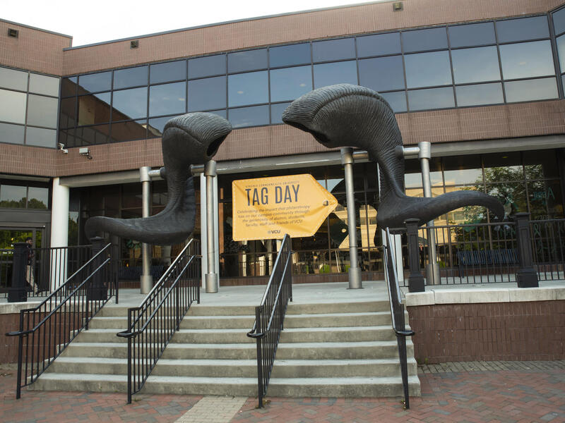 A sign celebrating Tag Day under the ram horn sculpture in front of the University Student Commons building.