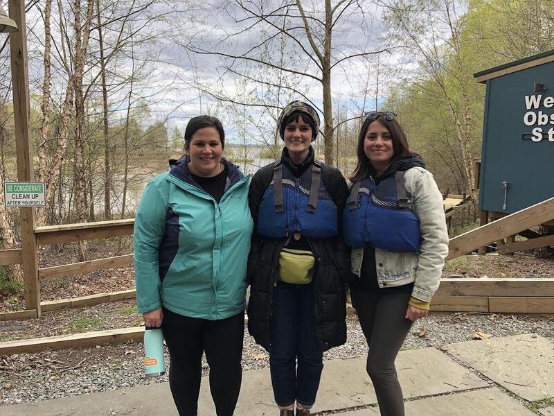 Three women in warm clothes stand next to each other.