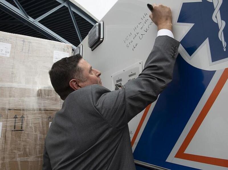 A man in a suit writing a message on an ambulance 