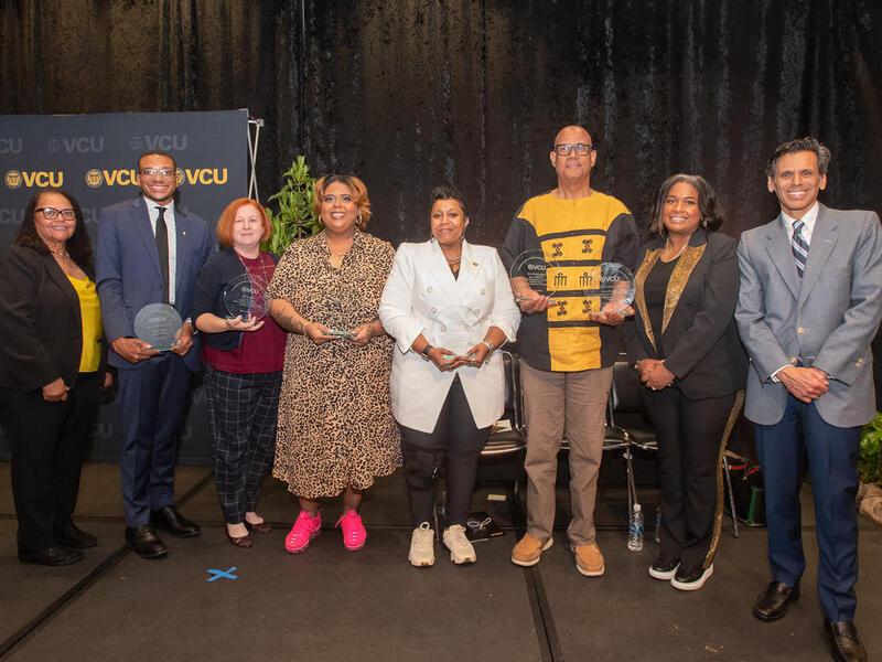 A group photo of eight people standing on a stage. 