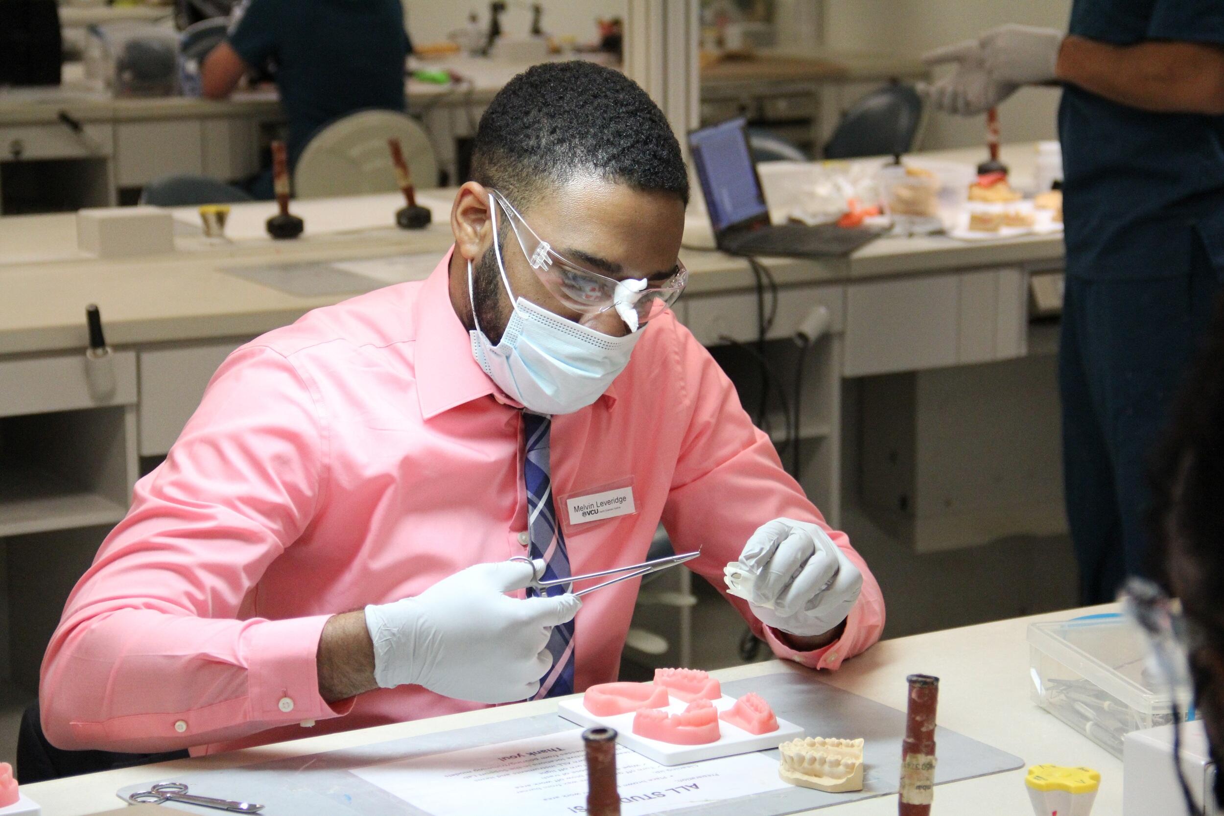 Melvin Leveridge sitting at a table while wearing gloves, a face mask, and protective glasses. 
