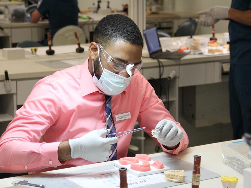 Melvin Leveridge sitting at a table while wearing gloves, a face mask, and protective glasses. 
