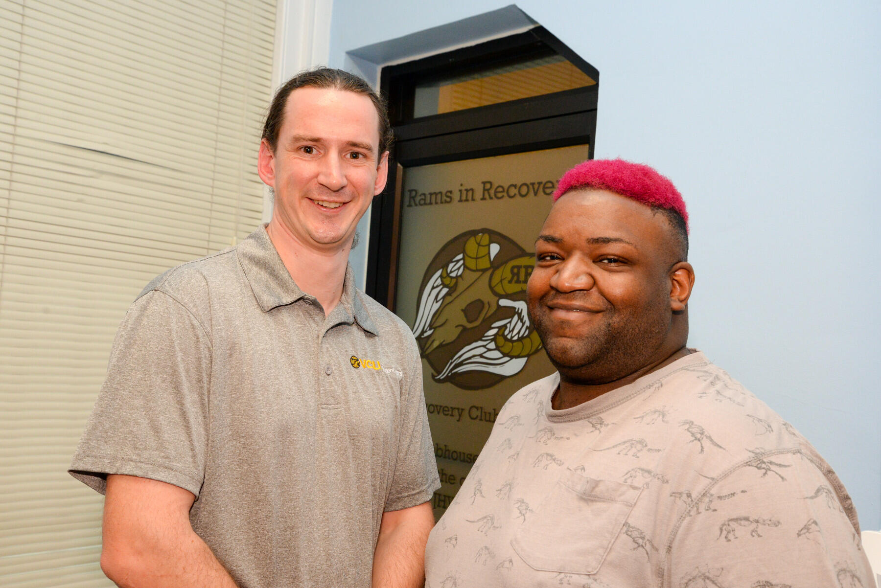 Two men standing by a door reading "Rams in Recovery."