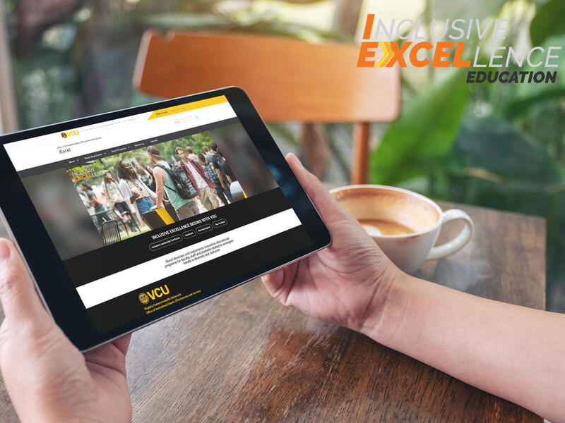 Hands resting on a table while holding an ipad. In the upper left corner is text that reads \"Inclusive Excellence Education\" 