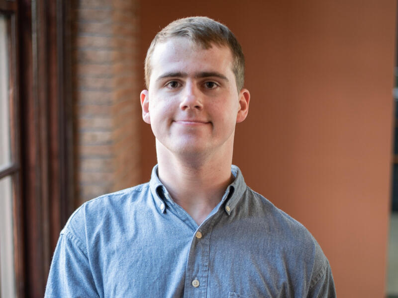 A head and shoulders image of a man in a blue button-down shirt.