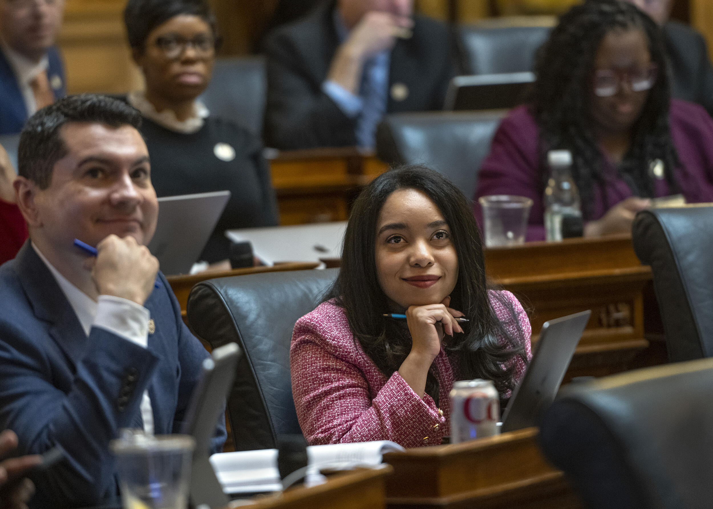 A man and woman sitting in chairs at a desk on the state house floor.
