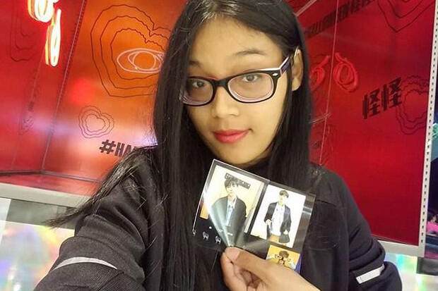 A woman holds a postcard in front of a red background.