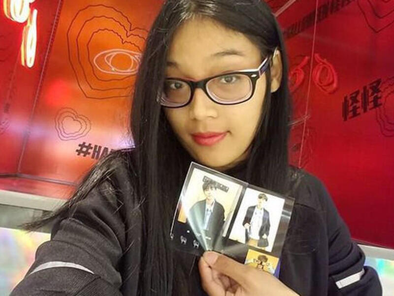 A woman holds a postcard in front of a red background.