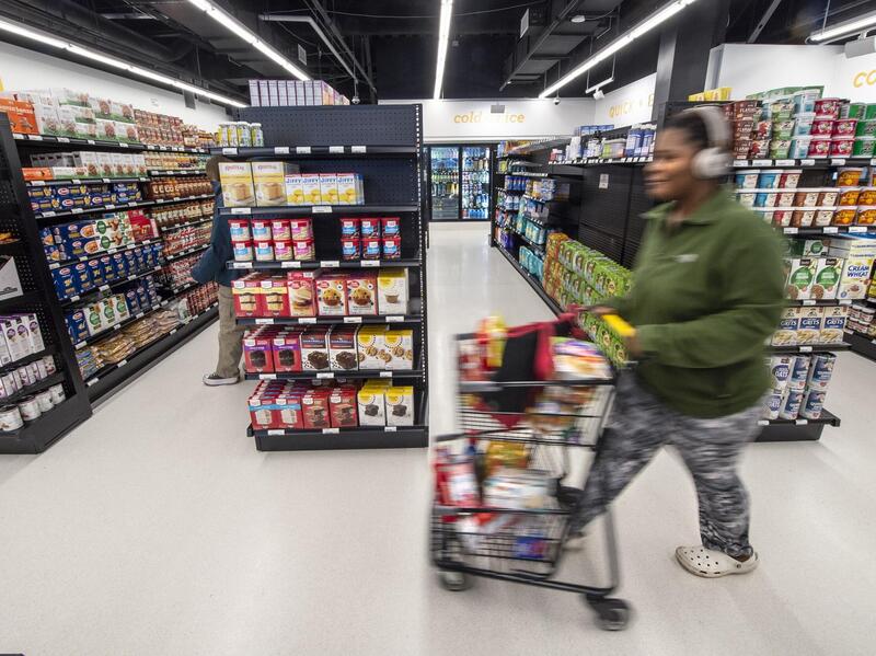 A person walking a cart full of groceries through a grocery store 
