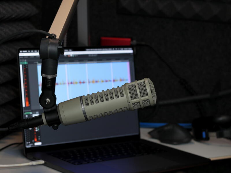 A photo of a microphone in front of a laptop screen. 
