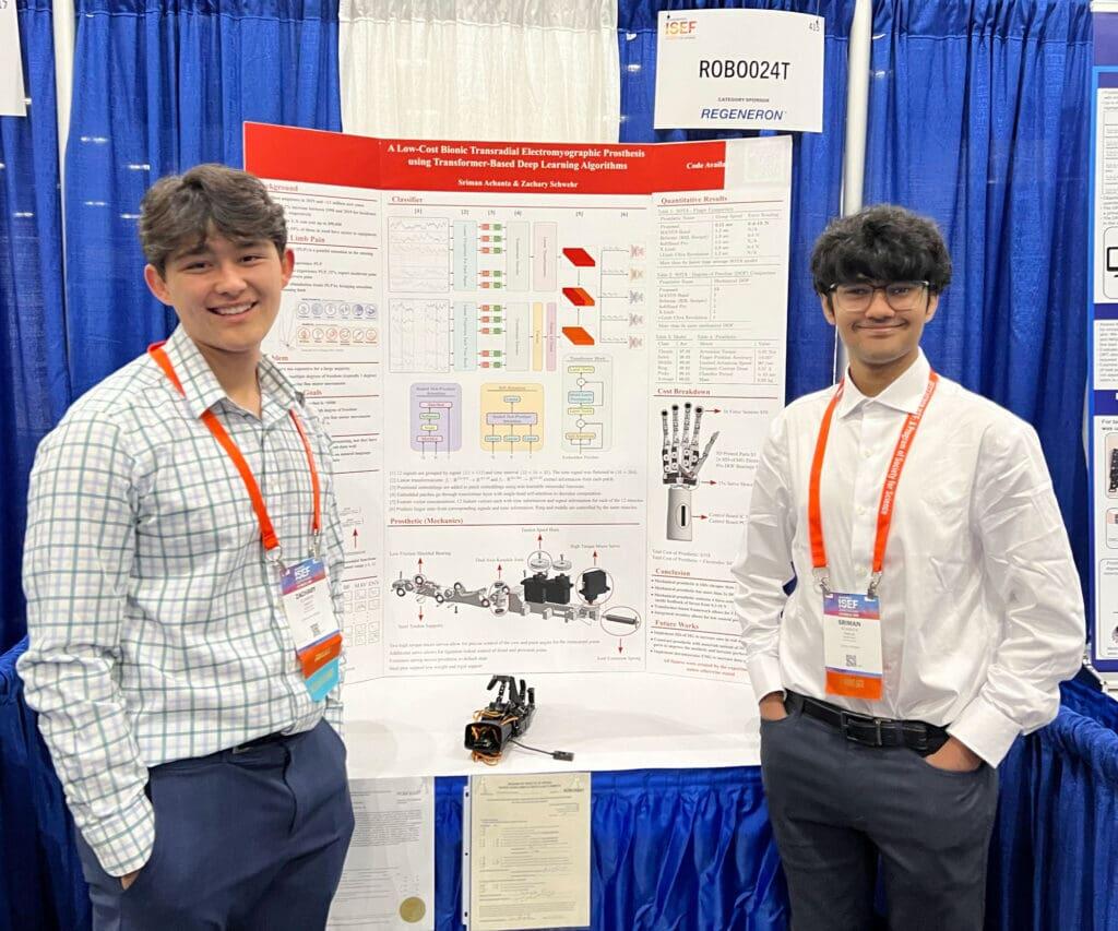 A photo of two men standing on either side of a poster. 