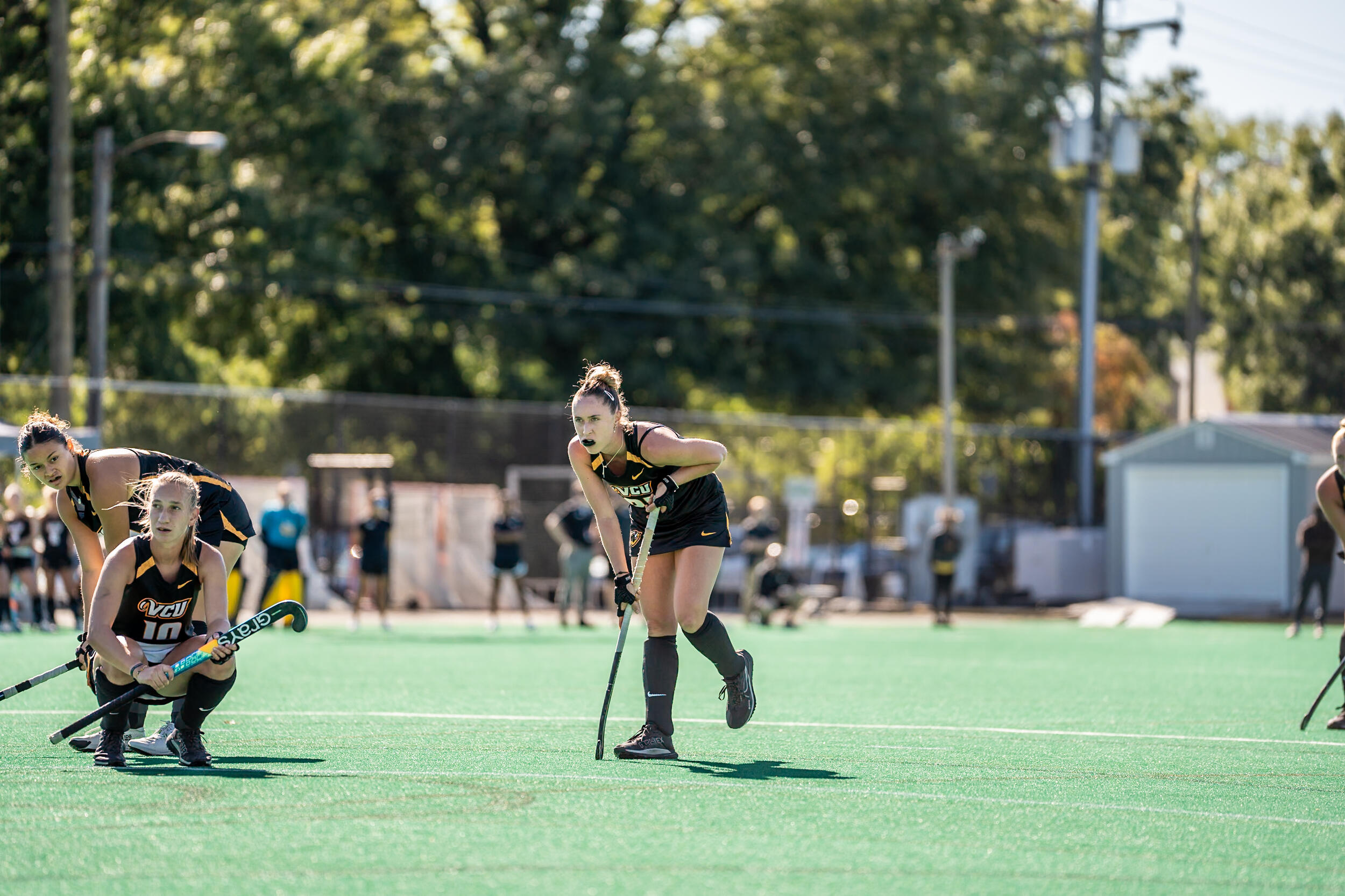A photo of three women kneeling on a field. 
