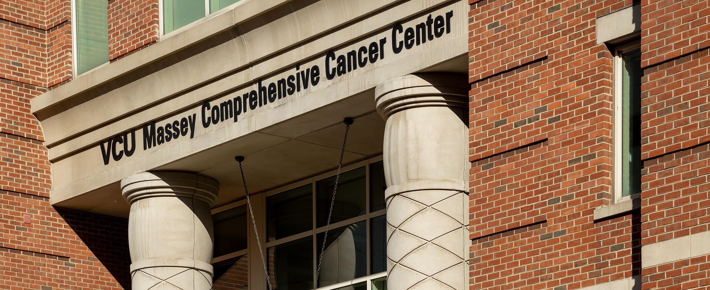A photo of the front of a building. Above the archway to the door are black letters that spell out \"VCU Massey Comprehensive Cancer Center.\"