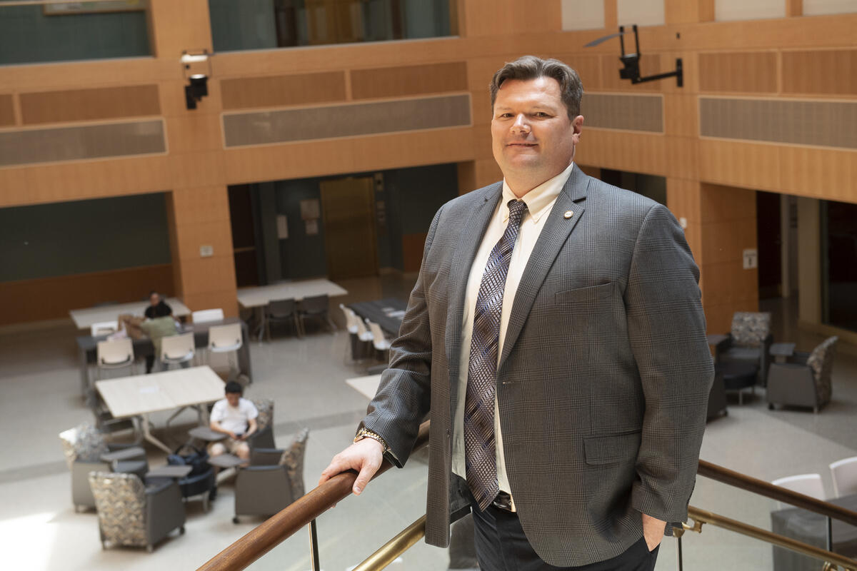 A man wearing a suit and tie standing with his hand resting on a stair railing 