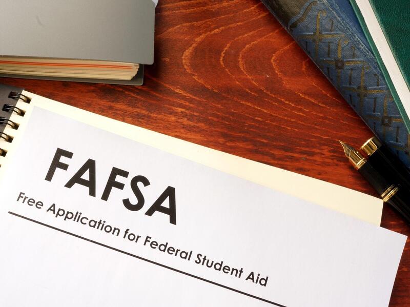A piture of a white piece of paper that says \"FAFSA Free Application for Federal Student Aid\" on top of a notebook on a desk