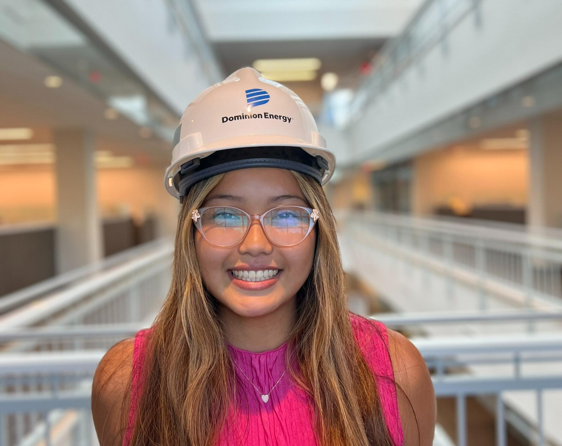 A portarait of a woman wearing a hard hat and safety glasses 