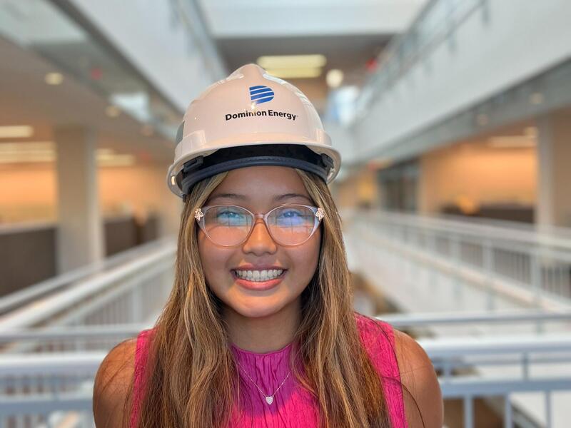 A portarait of a woman wearing a hard hat and safety glasses 