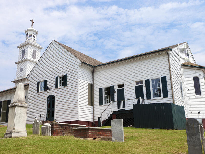 A photo of a church with a small graveyard in front of it. 