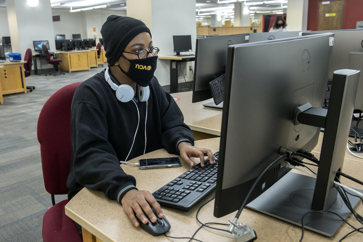 A student working at a computer station inside Cabell Library.