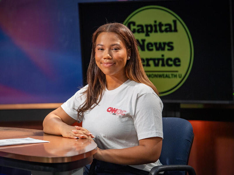 A photo of a woman sitting at a desk.