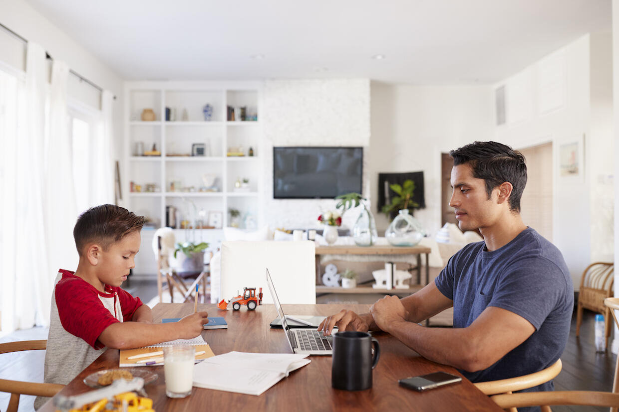 A child and a young adult sit at a table doing work.