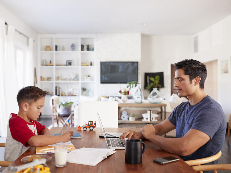 A child and a young adult sit at a table doing work.