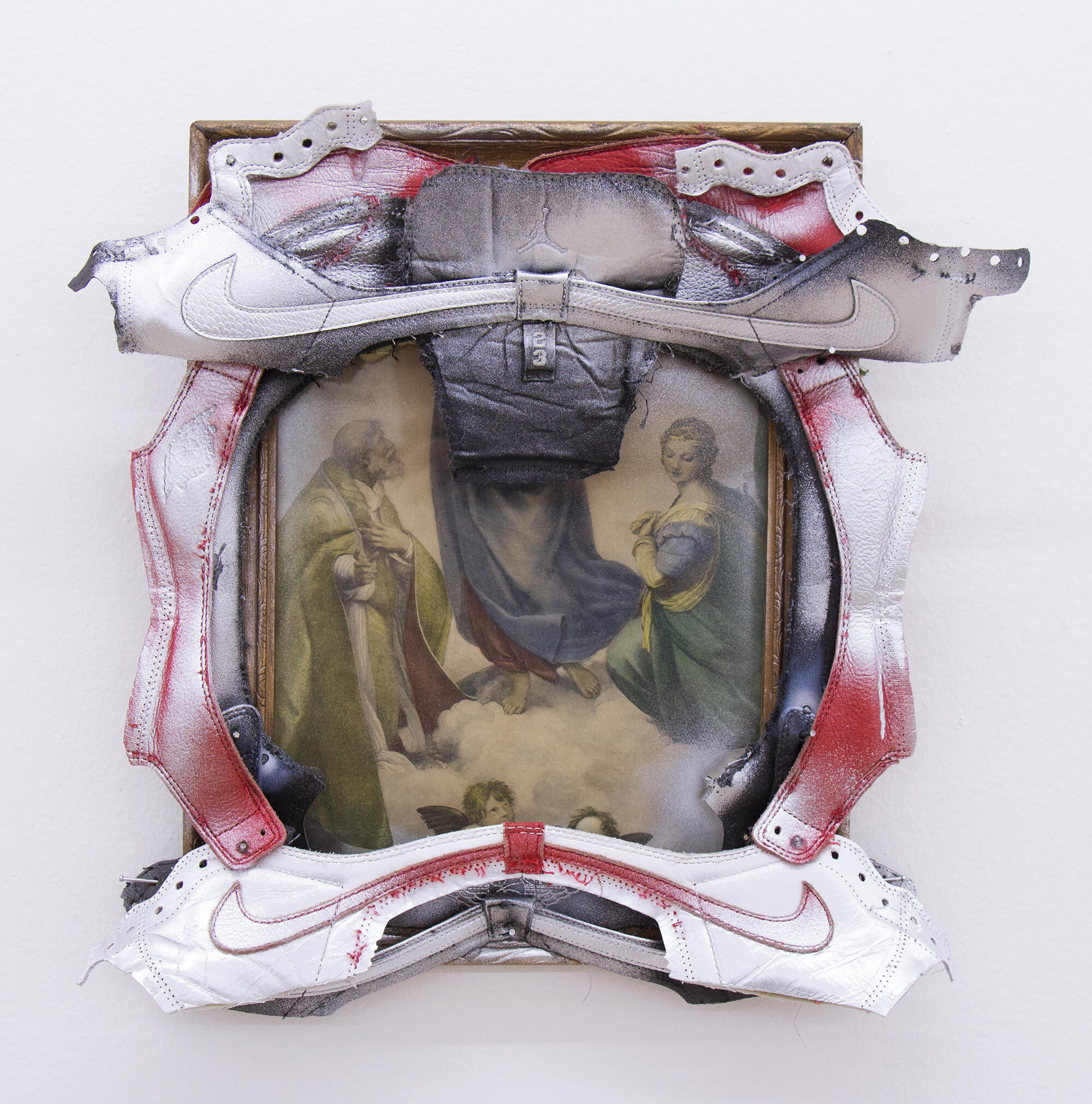 A photo of a religious painting framed with cut-up Nike sneakers. 