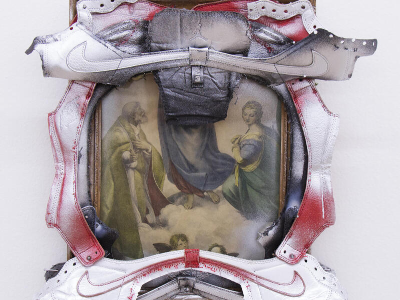 A photo of a religious painting framed with cut-up Nike sneakers. 