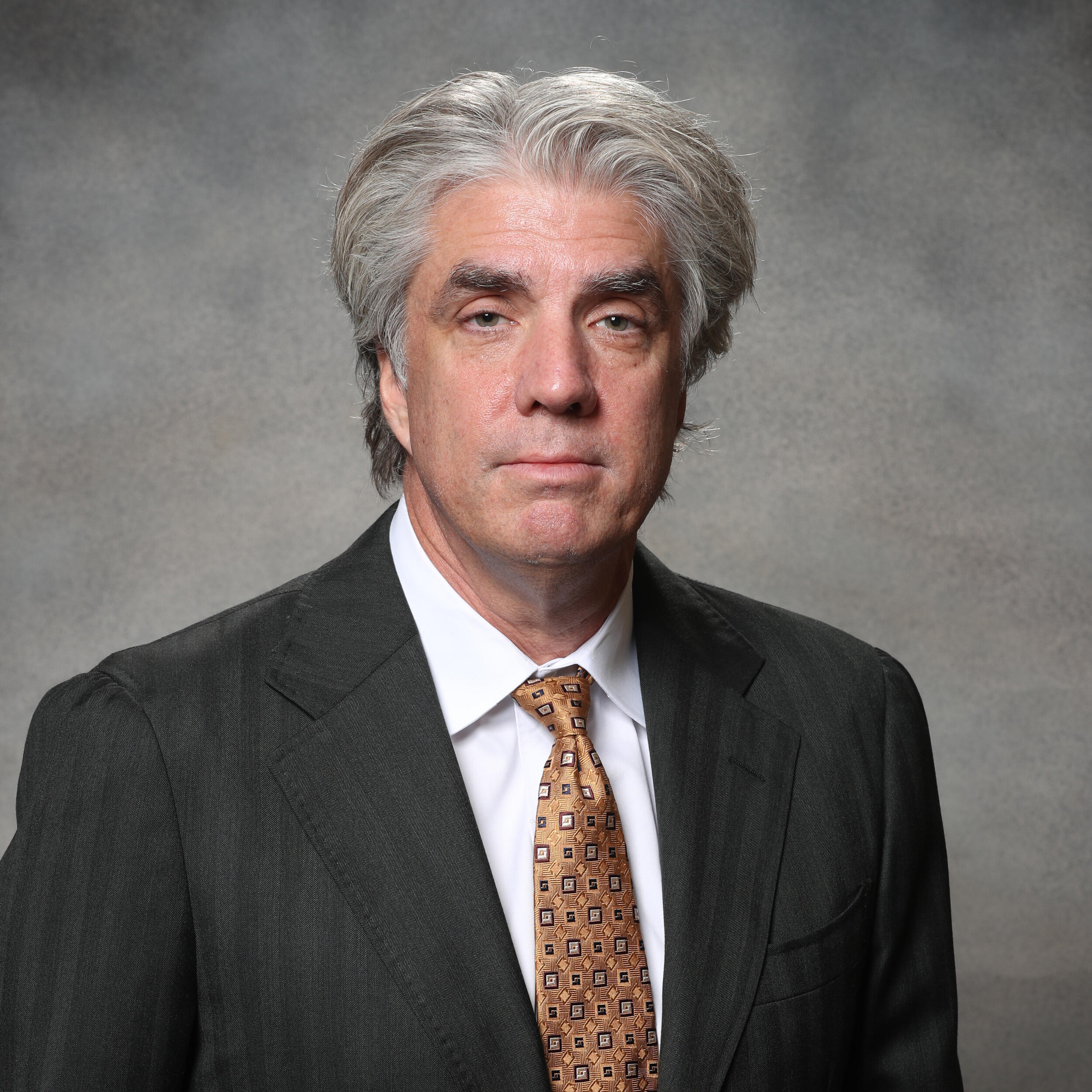 A photo of a man wearing a suit and tie from the chest up. 