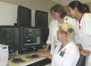 Cardiac monitor tech Marta Egressy (left), Sue Harrison, nurse manager and nurse Saima Panjwani assess a patient's cardiac status from telemetry information available on monitors in intermediate medicine on the 9th floor of North Hospital.

Photos by Michael Ford, University News Services