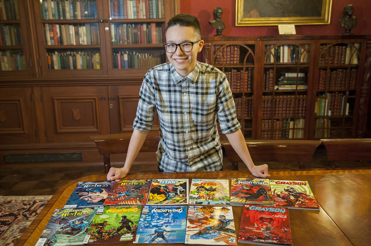 A person standing behind a tabletop with various comic books.