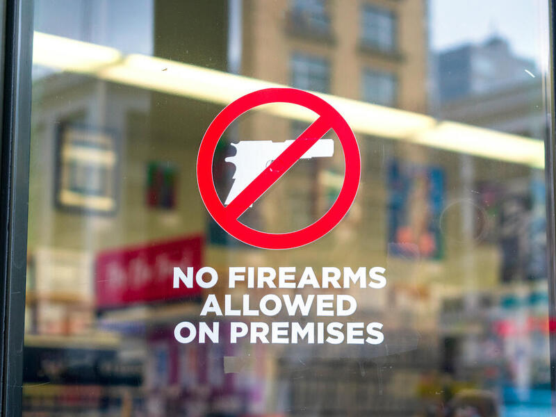 A sign on a window with a gun crossed out. The text below reads \"No firearms allowed on premises.\"