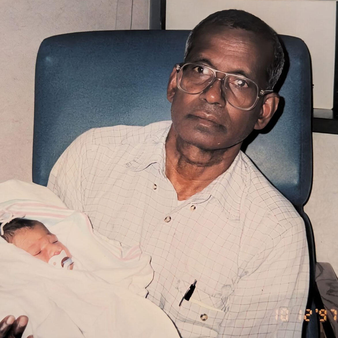 A photo of a man wearing glasses holding a baby. 