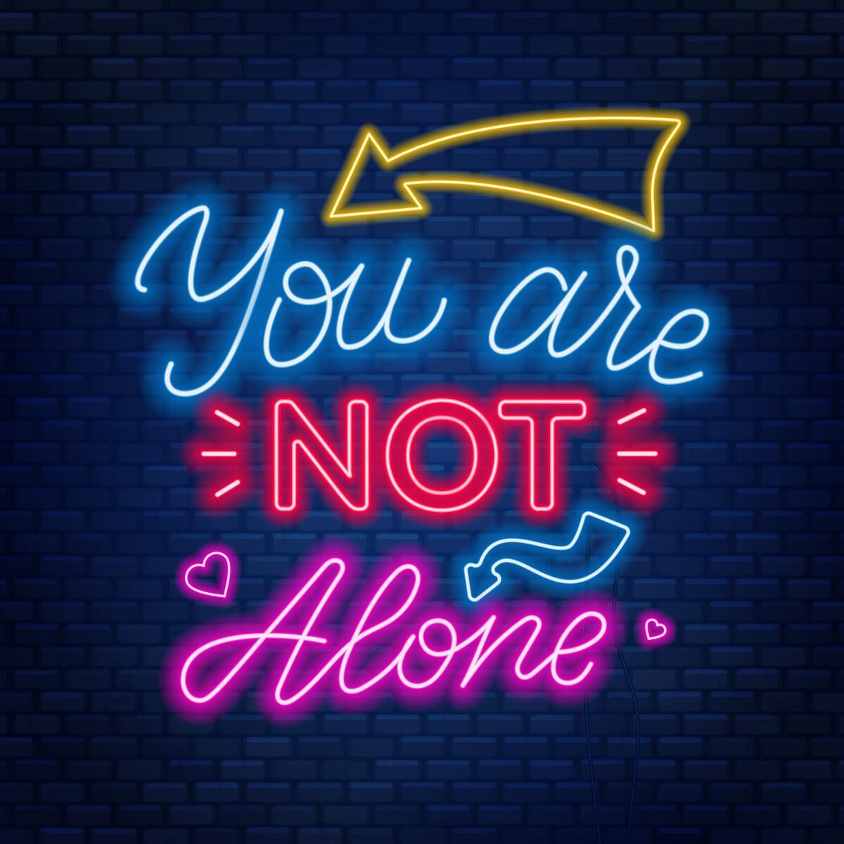 Neon letters that spell out \"Y-o-u a-r-e n-o-t a-l-o-n-e.\" 