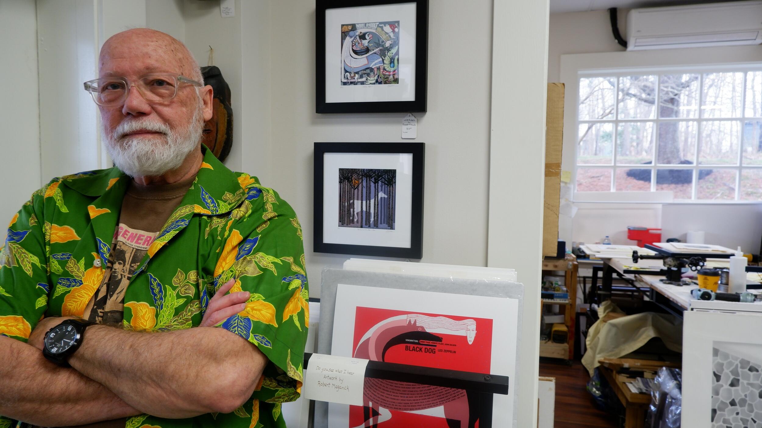Robert Meganck standing with his arms crossed. He is wearing glasses, a green button up short sleeve shirt and a black wrist watch. 