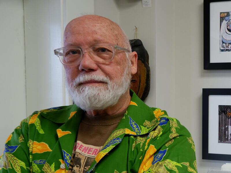 Robert Meganck standing with his arms crossed. He is wearing glasses, a green button up short sleeve shirt and a black wrist watch. 