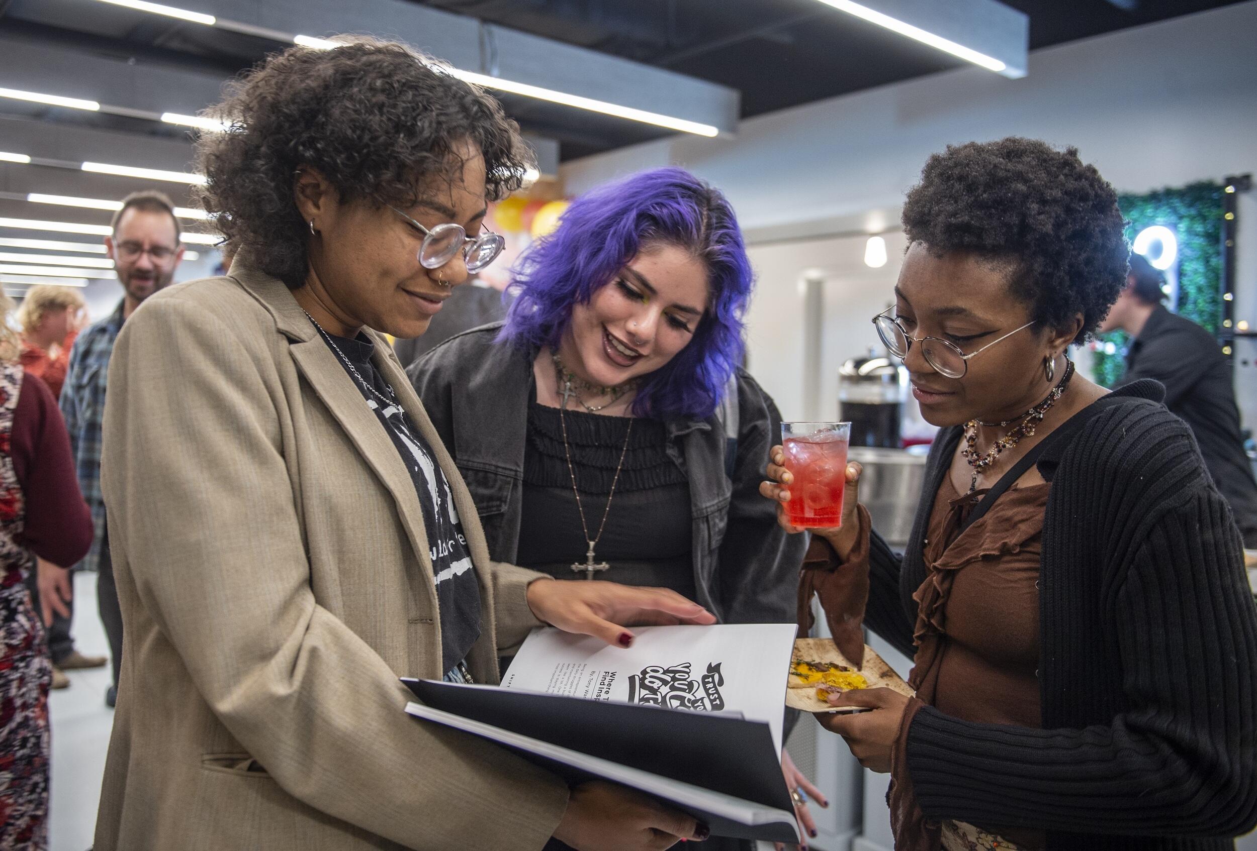 Three people looking at a magazine 