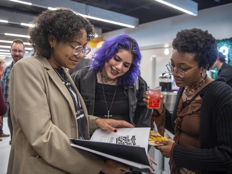 Three people looking at a magazine 